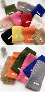 Close-up of thick knitted scarves in multiple colors with brand logo fabric labels