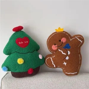 Detail of plush Christmas tree and gingerbread man pillows on a soft grey sofa