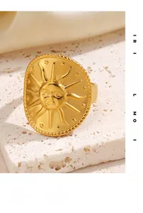 Detailed close-up of golden sun relief ring with star elements on a textured white stone