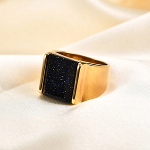 Detailaufnahme eines breiten goldenen Edelstahlrings mit rechteckigem blauem Sandstein