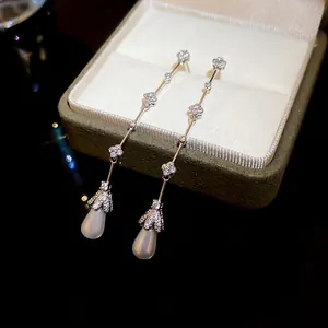 Silver drop earrings with flower charms and teardrop pearls on a jewelry box