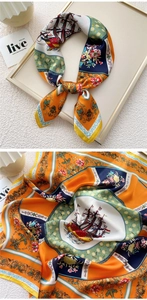 Detailed view of square silk scarf with orange nautical prints and baroque floral patterns