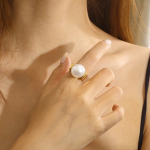 Moderner breiter goldener Edelstahlring mit großer weißer Rundperle an der Hand