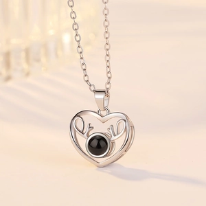 Detail of silver heart necklace with deer antlers and black projection stone pendant