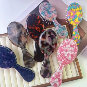 Mini acetate hair brushes with colorful patterns on soft velvet cushion