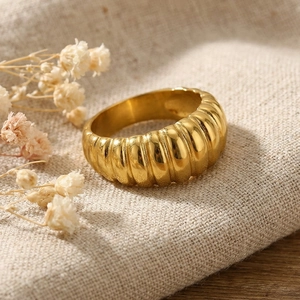 Macro view of gold-plated croissant ribbed stainless steel ring on linen background