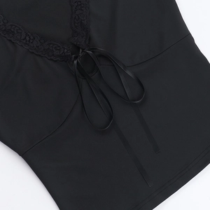Detailed macro view of black lace trim and satin bow tie on a trendy streetwear top
