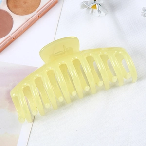 Detailed view of large translucent yellow geometric hair claw clip on soft fabric