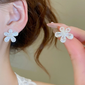 Detailed view of silver flower earrings with clear zircon petals and center pearl