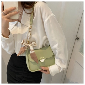 Mirror selfie showing an avocado green crossbody bag with a decorative floral silk scarf