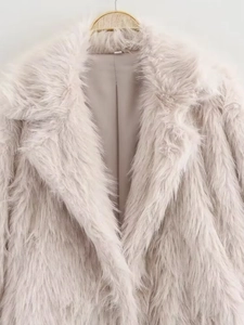 Detail of faux fur lapel coat in light beige showing soft plush texture on hanger