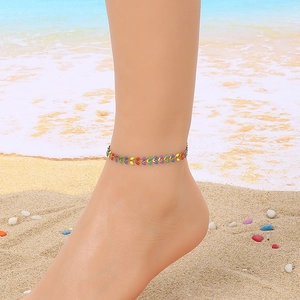Close-up of a colorful enamel fishtail anklet on ankle with a beach holiday background