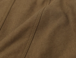 Detailed macro view of dark brown twill fabric with precise double-needle stitching quality
