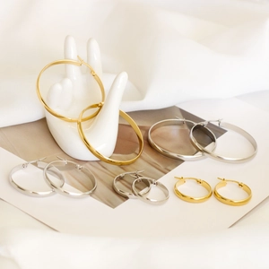 Detail showing various sizes of gold and silver hoop earrings on a hand prop