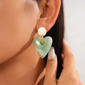 Detailed view of a green heart-shaped resin pendant necklace with gold metallic beads