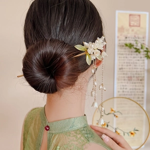 Close-up of lily of the valley hair pin with gold tassels on model in traditional dress