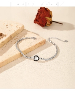Detail of silver tennis bracelet with black heart charm and sparkling zircon stones