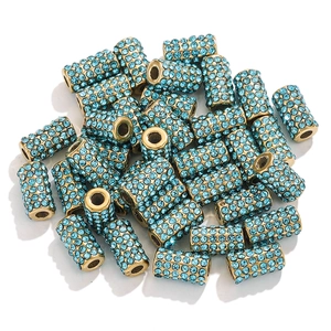 Detailed view of golden cylinder beads with blue rhinestones for DIY jewelry making
