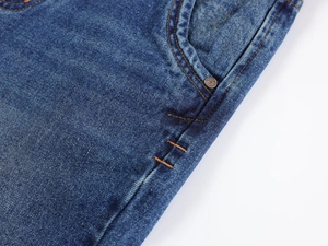 Detailed macro view of denim pocket featuring metal rivets and reinforced stitching
