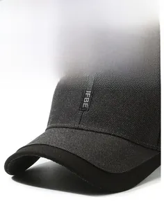 Détail macro de la casquette gris foncé montrant le patch brodé JFBE et la texture tissée