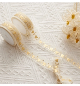 Detail of semi-transparent cream organza ribbons with gold foil heart patterns for gift wrapping