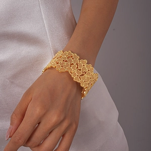 Détail du bracelet doré évidé présentant des motifs floraux délicats et un travail soigné