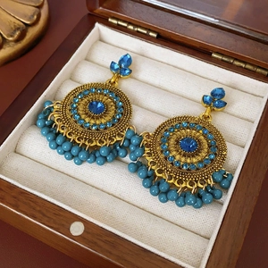 Close-up of vintage golden Jhumka earrings with blue rhinestones and bead tassels
