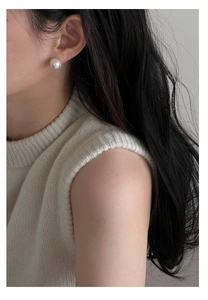 Close-up of elegant pearl stud earring on a silver textured base worn by a model