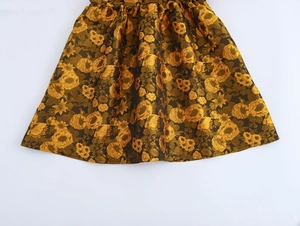 Detailed macro view of golden jacquard floral pattern on flared skirt with rich texture