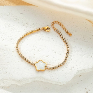 Detailed macro view of golden stainless steel bracelet with white flower pendant on silk