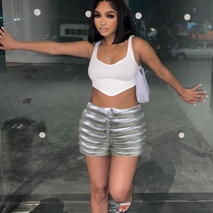 Detail of shiny silver metallic puffer shorts and white crop top in a night outdoor setting