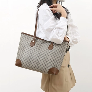 Large beige and brown tote bag with vintage pattern and leather trim on a model