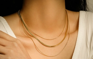 Close-up of triple-layered golden snake chains on neck with polished metal texture