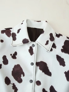 Detail of cow print jacket featuring matte black buttons and reinforced zigzag stitching
