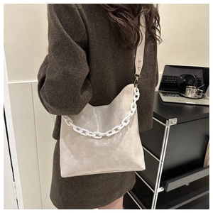 Detail view of winter beige crossbody bag with chunky white chain and fabric strap