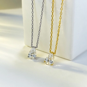 Macro detail of pear-cut crystal pendants in gold and silver finishes on geometric blocks
