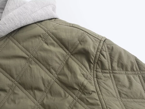 Detail shot of olive green diamond-quilted nylon fabric and grey hood stitching