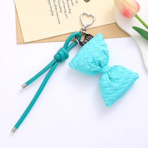 Close-up of cyan puffy bow keychain with heart clasp and leather strap on vintage paper