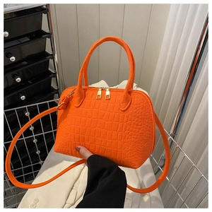 Macro view of bright orange crocodile texture leather bag with golden metal zipper detail