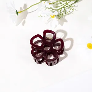 Detail of dark red floral hair claw clip with golden spring on white flower background