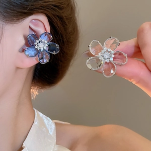 Detailed view of zircon flower ear cuffs with blue and clear crystals on a model's ear