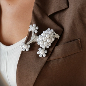 Macro shot of silver poodle brooch with faux pearls and rhinestones on a brown suit jacket