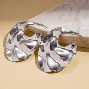 Gros plan de boucles d'oreilles en métal argenté irrégulier sur support minimaliste