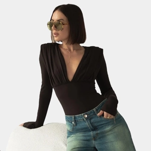 Detail view of black deep V-neck bodysuit with shoulder pads and ruched fabric design