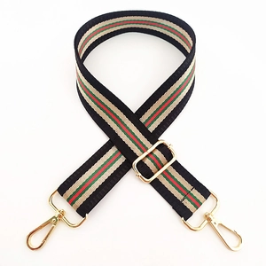 Detail of adjustable striped bag strap with gold metal hooks and durable weaving texture