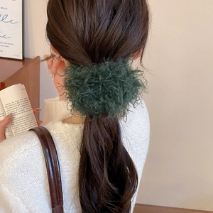Detail of dark green plush scrunchie worn on a low ponytail for a warm winter look