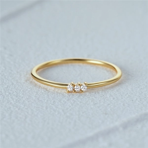 Macro shot of minimalist 18K gold ring featuring three small zircon stones on thin band