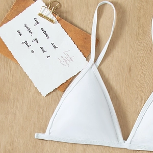 Minimalist white triangle bikini top with adjustable straps on a natural wooden background