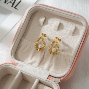 Nahaufnahme goldener unregelmäßiger Wellenohrringe mit Perlen in rosa Leder Schmuckbox