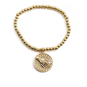 Gold beaded stretch bracelet featuring a palm charm with clear zircon on white background